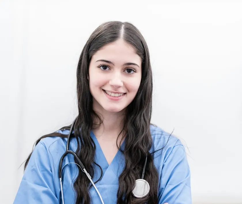 A smiling NHS nurse in blue scrubs
